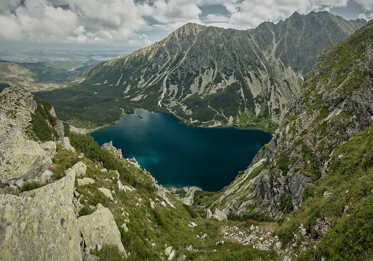 Widok na szczyt w dolinie gąsienicowej, z turkusowym jeziorem i skalistymi zboczami.