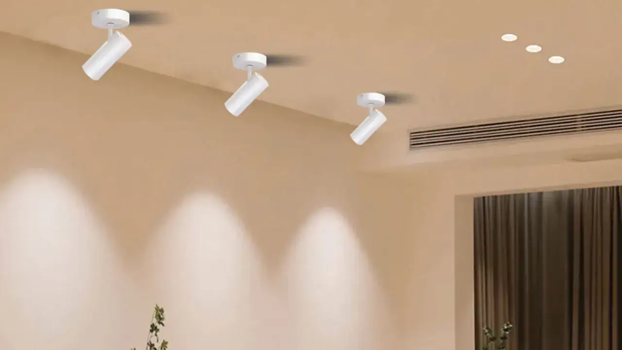 Tres focos orientables techo blancos iluminan la pared, creando un ambiente acogedor.