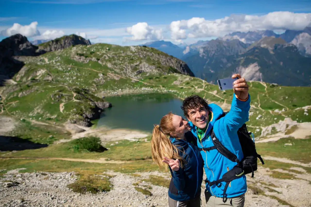 Coppia felice si scatta un selfie con il lago e le montagne sullo sfondo, vicino al rifugio Coldai.