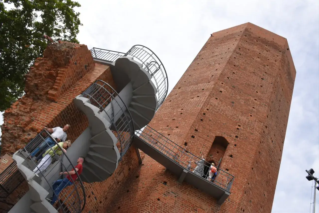 Miasto z mysią wieżą. Ludzie wchodzą po spiralnych schodach na zabytkową wieżę, podziwiając widoki.