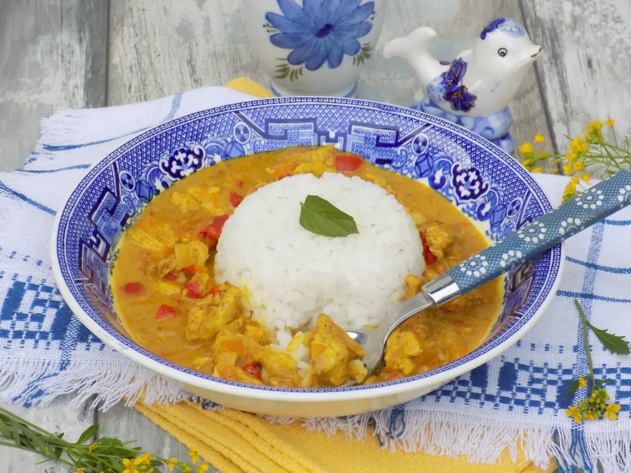 Pyszny kurczak curry z ryżem, podany w ozdobnej misce, z widelcem gotowym do degustacji.