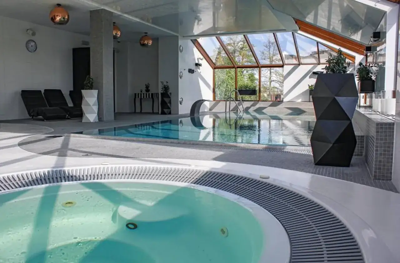 Relaks w basenie i jacuzzi w hotelu Willa Port w Ostródzie. Duże okna zapewniają widok na zieleń.