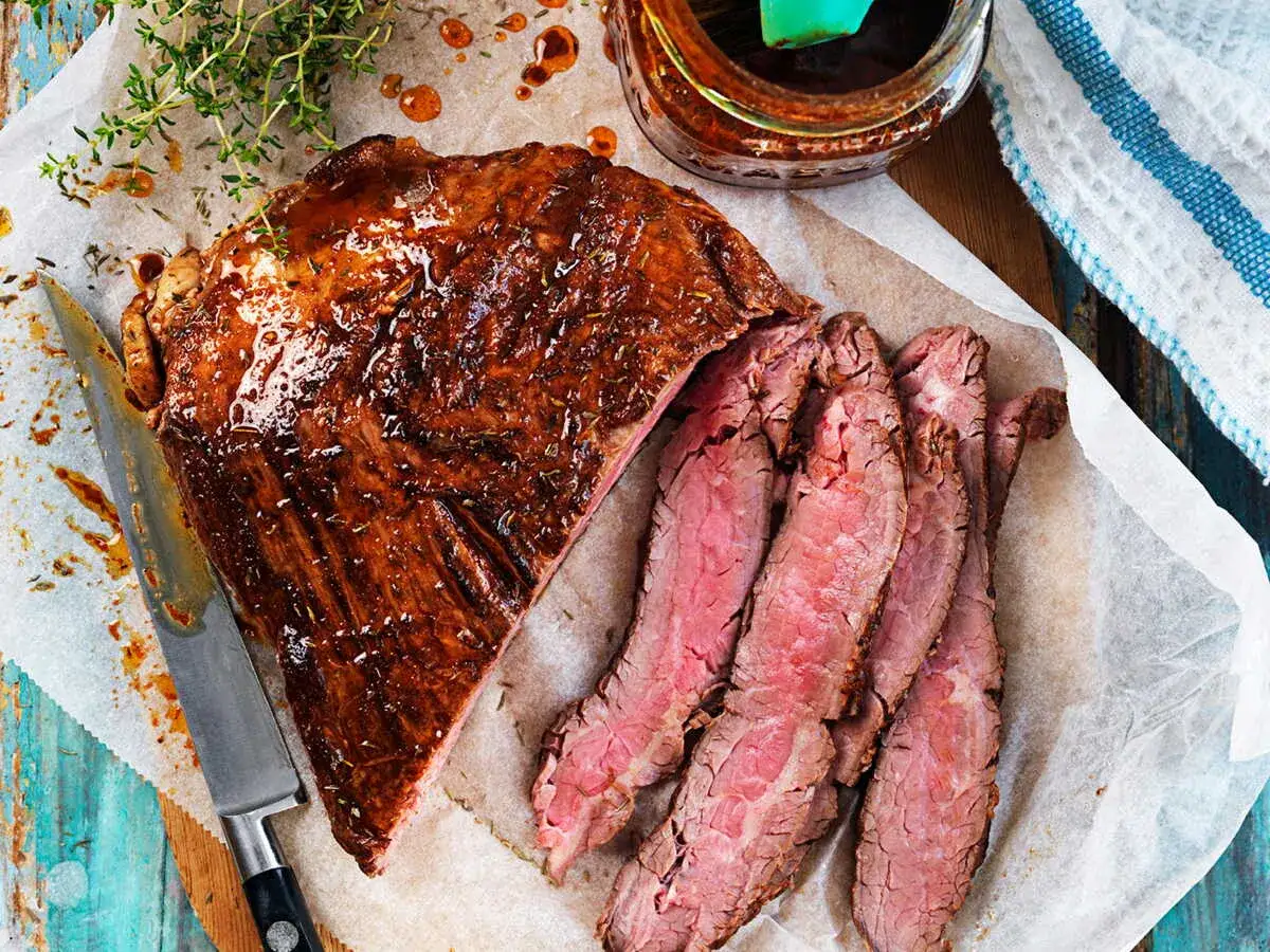 Un pavé de rumsteak juteux, tranché et nappé d'une sauce brillante, prêt à être dégusté.