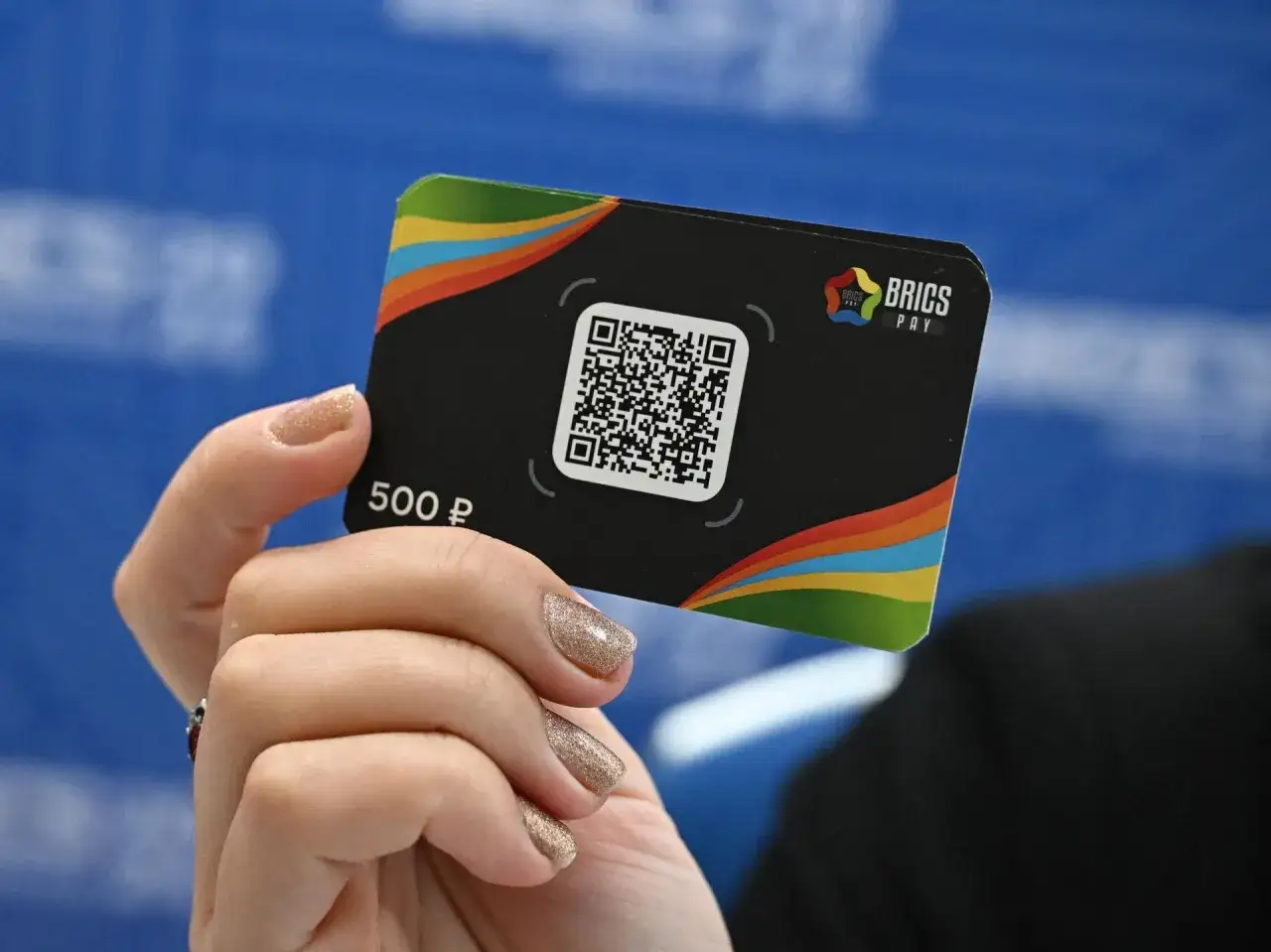 Dłoń trzyma kartę z logo BRICS PAY i kodem QR. To symbol nowej waluty BRICS, która może zrewolucjonizować finanse.