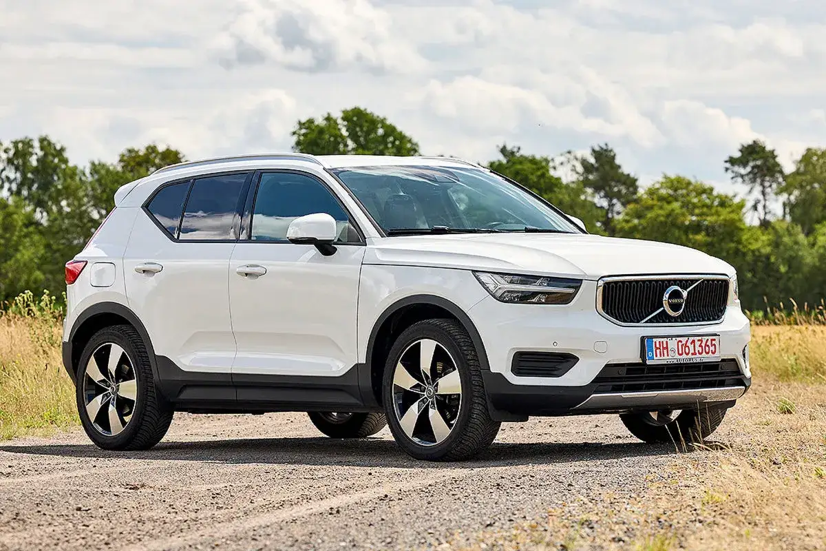 Weißer Volvo XC40 auf Schotterweg, umgeben von Bäumen und Feldern. Ein Blick auf das Fahrzeug, das trotz möglicher Volvo XC40 Probleme eine gute Figur macht.