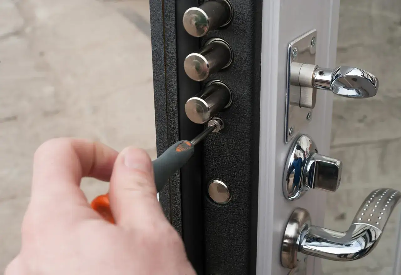 Mano con cacciavite che lavora su una serratura di sicurezza. Pronto a sostituire serratura.