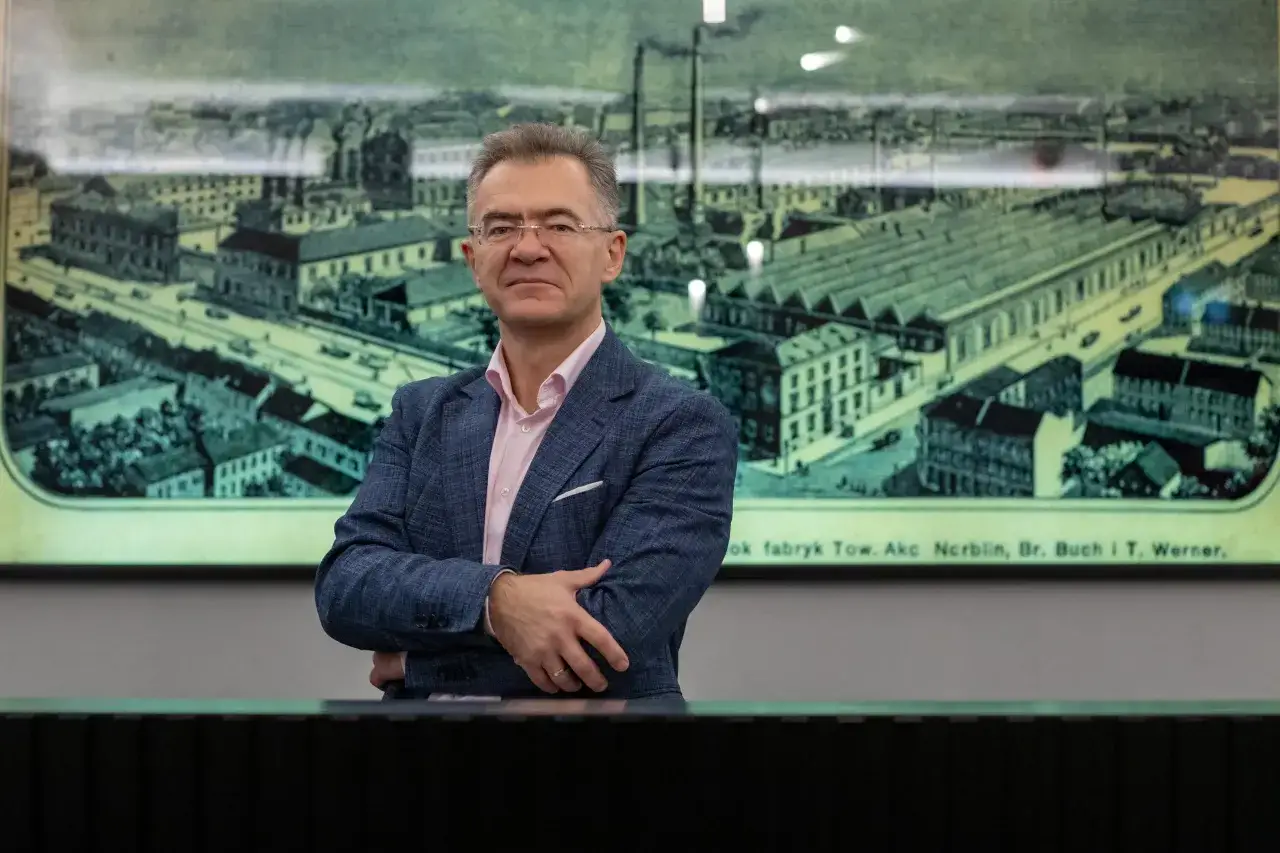 Mężczyzna w garniturze na tle historycznego obrazu miasta. Rozumie, asset management co to, jak zarządzać zasobami.