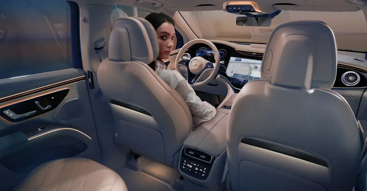Kobieta siedzi za kierownicą luksusowego **Mercedes EQS SUV**, otoczona nowoczesnym, podświetlanym wnętrzem.