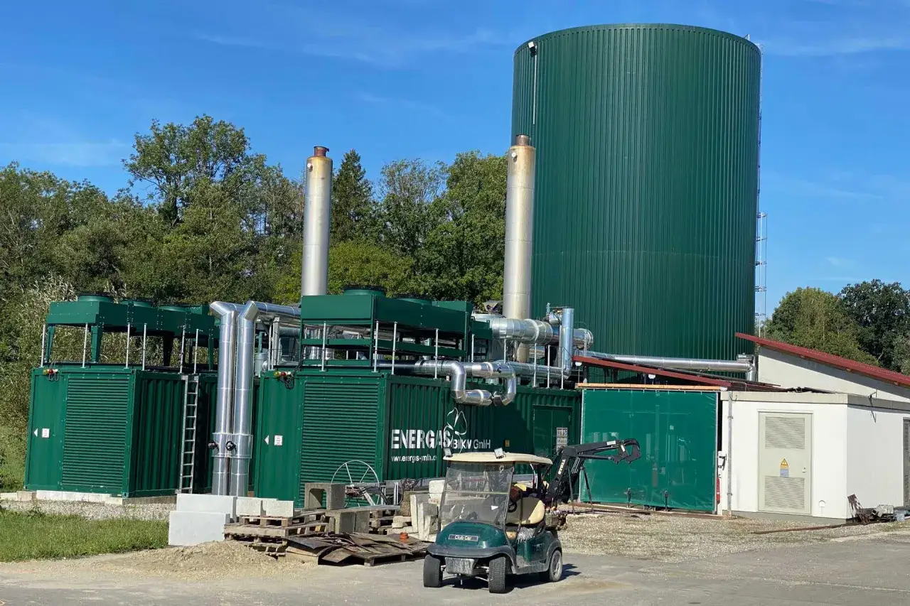 Gro&szlig;e gr&uuml;ne Anlage zur Erzeugung von **biogas erneuerbare energie**. Ein Golfcart steht davor.