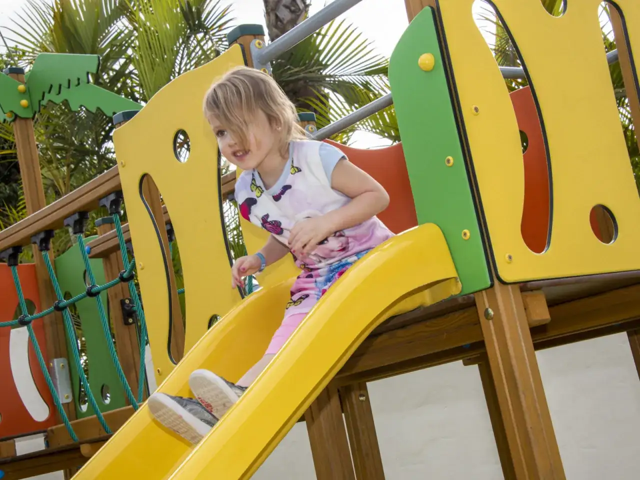Kleines Mädchen rutscht auf gelber Rutsche im TUI Kids Club Maspalomas Princess.