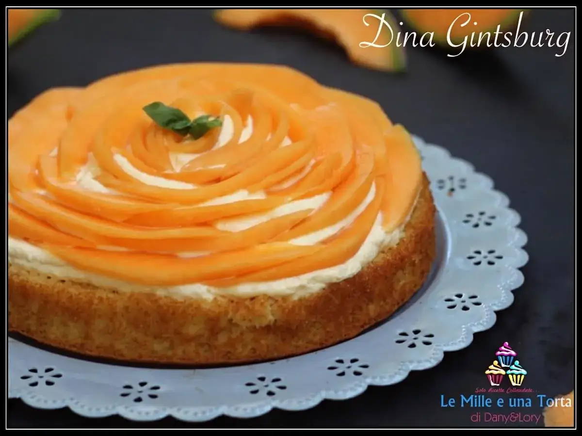 Torta soffice con crema al melone, decorata con fette di melone disposte a rosa e una fogliolina di menta.