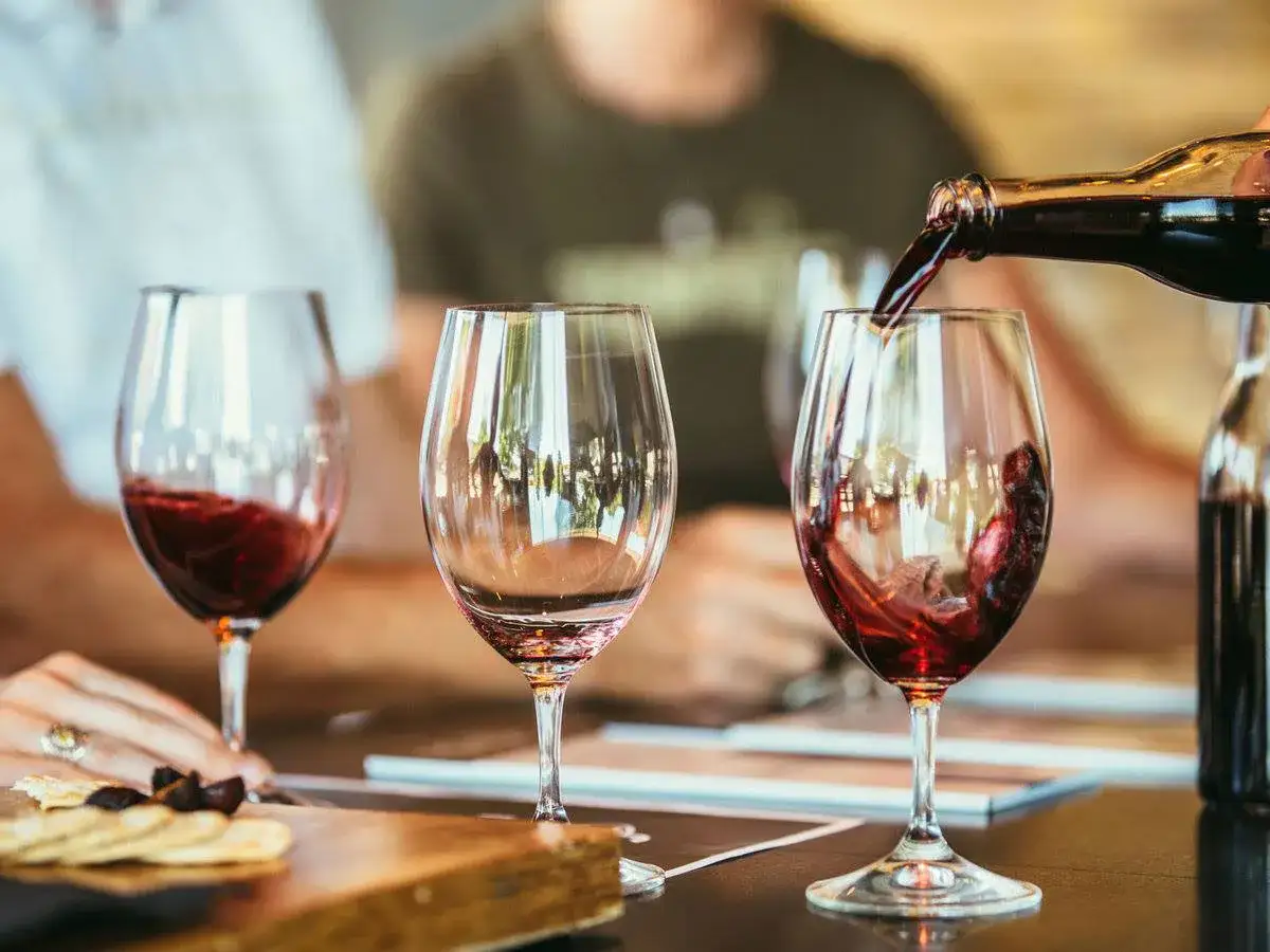 Degustazione di vino rosso alla fattoria di Piazzano. Un bicchiere viene riempito mentre altri due attendono.