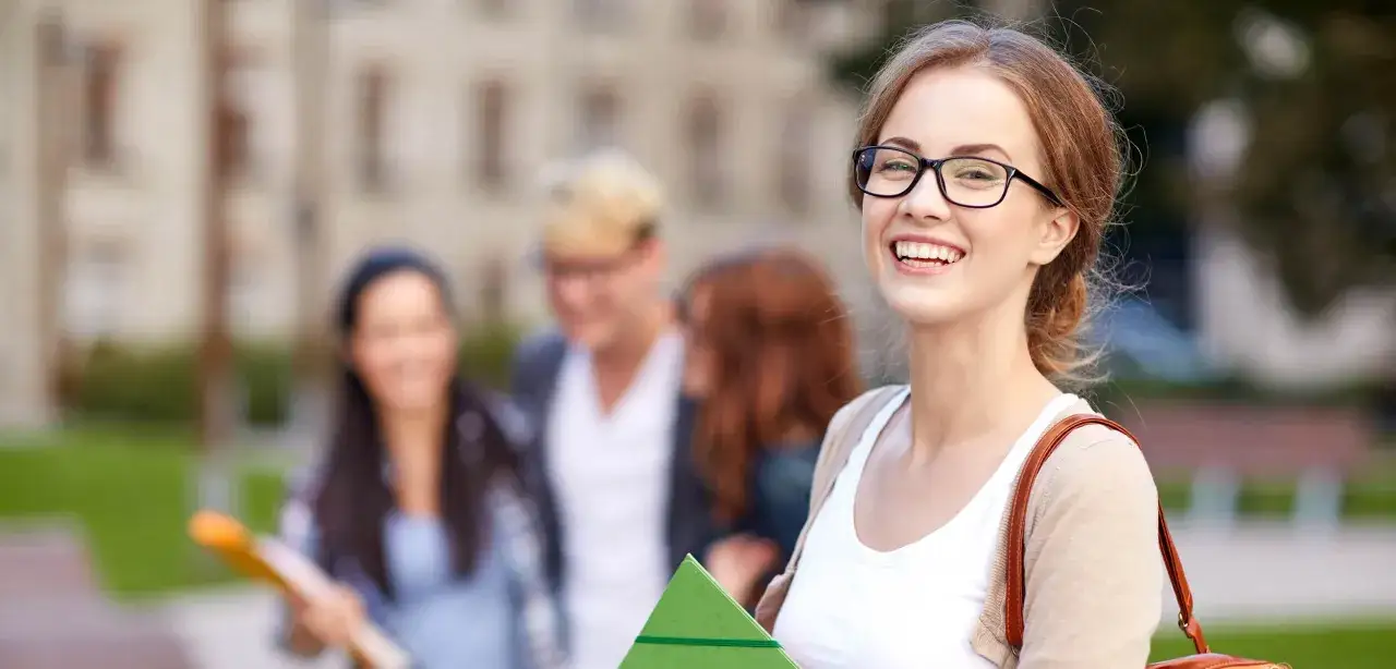 Glückliche Studentin mit Brille und Büchern, die sich über die sprachreise kosten informiert.