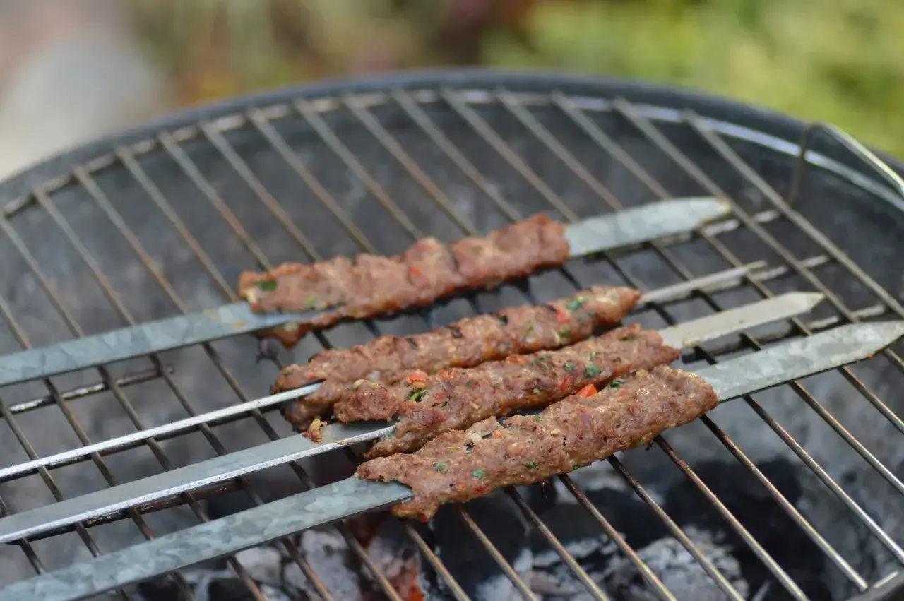 Irakisk kebab på grillen, med kryddor och grönsaker synliga. Doften av grillat sprider sig.