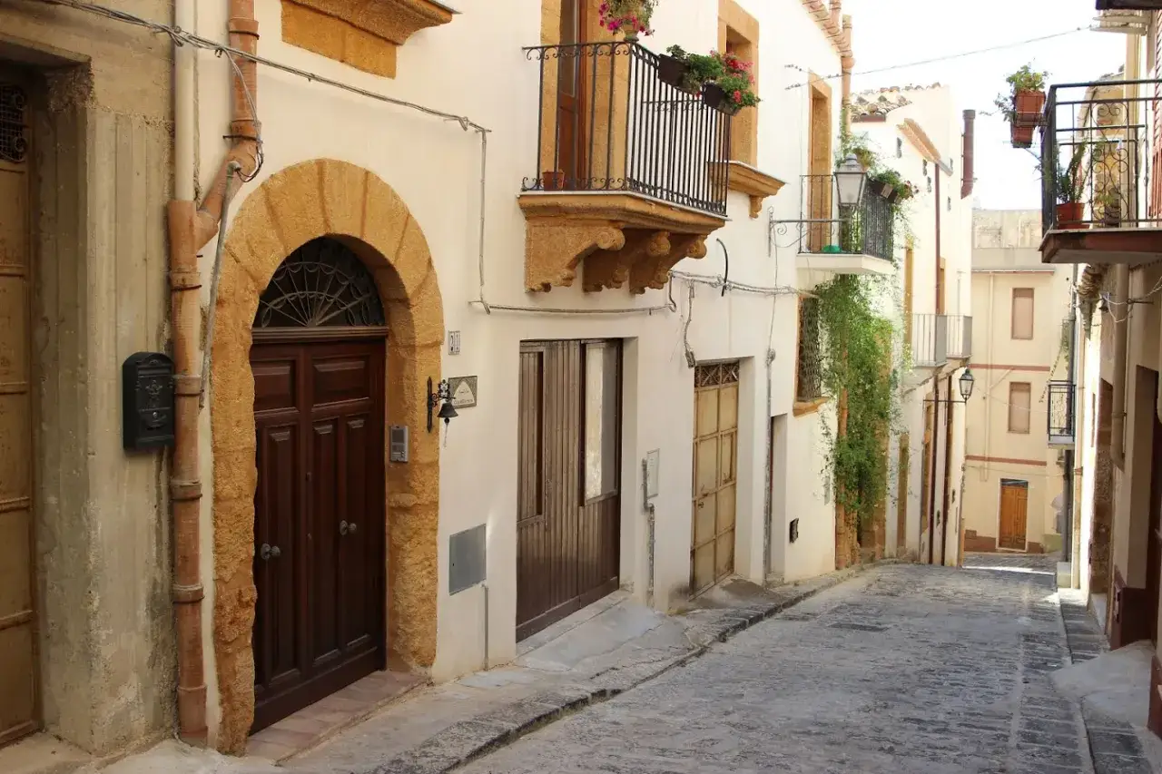 Un vicolo pittoresco a Sambuca di Sicilia, con portoni in legno scuro, balconi fioriti e scorci suggestivi. Ecco cosa vedere a Sambuca di Sicilia.