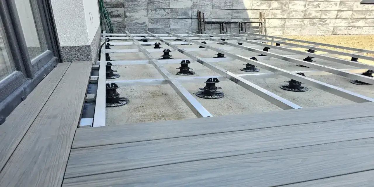Rozpoczyna się układanie deski kompozytowej na aluminiowym ruszcie z regulowanymi wspornikami.
