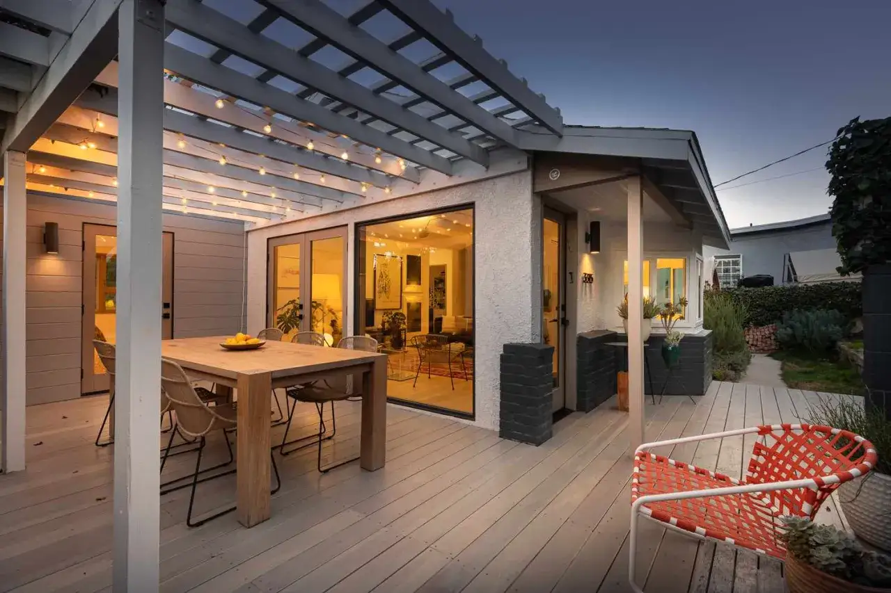 Gemütliche Beleuchtung Terrasse Ideen: Lichterketten über dem Essbereich und Wandleuchten schaffen stimmungsvolles Ambiente.