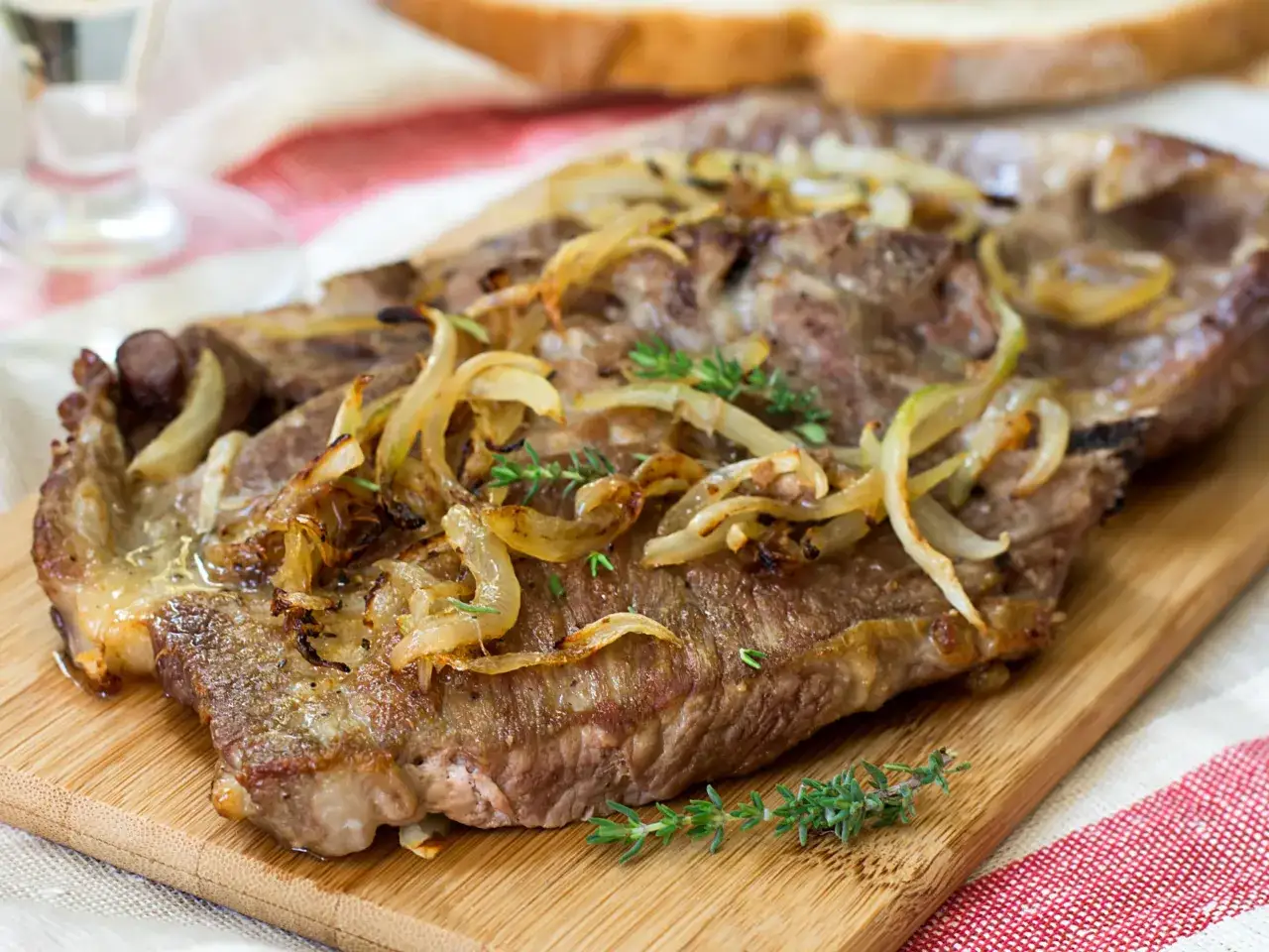 Steak savoureux garni d'oignons caramélisés et de thym frais, prêt à être dégusté. Une sauce steak oignon parfaite.