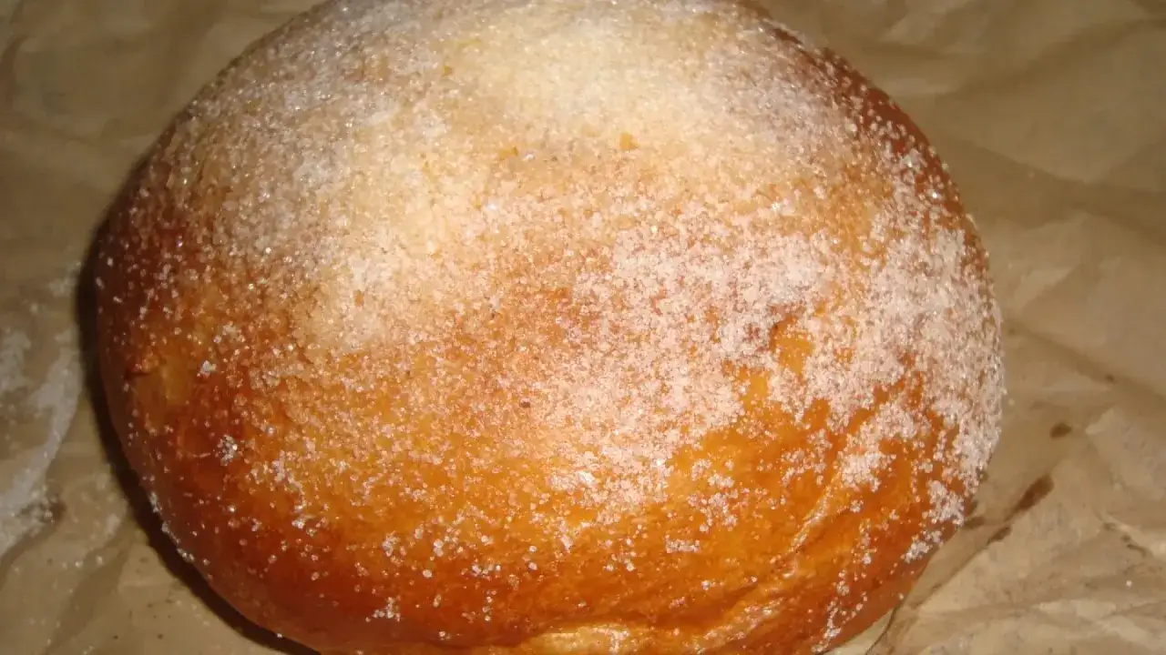 Un pan dulce espolvoreado con azúcar, con un ligero toque dorado que recuerda al pan quemado.
