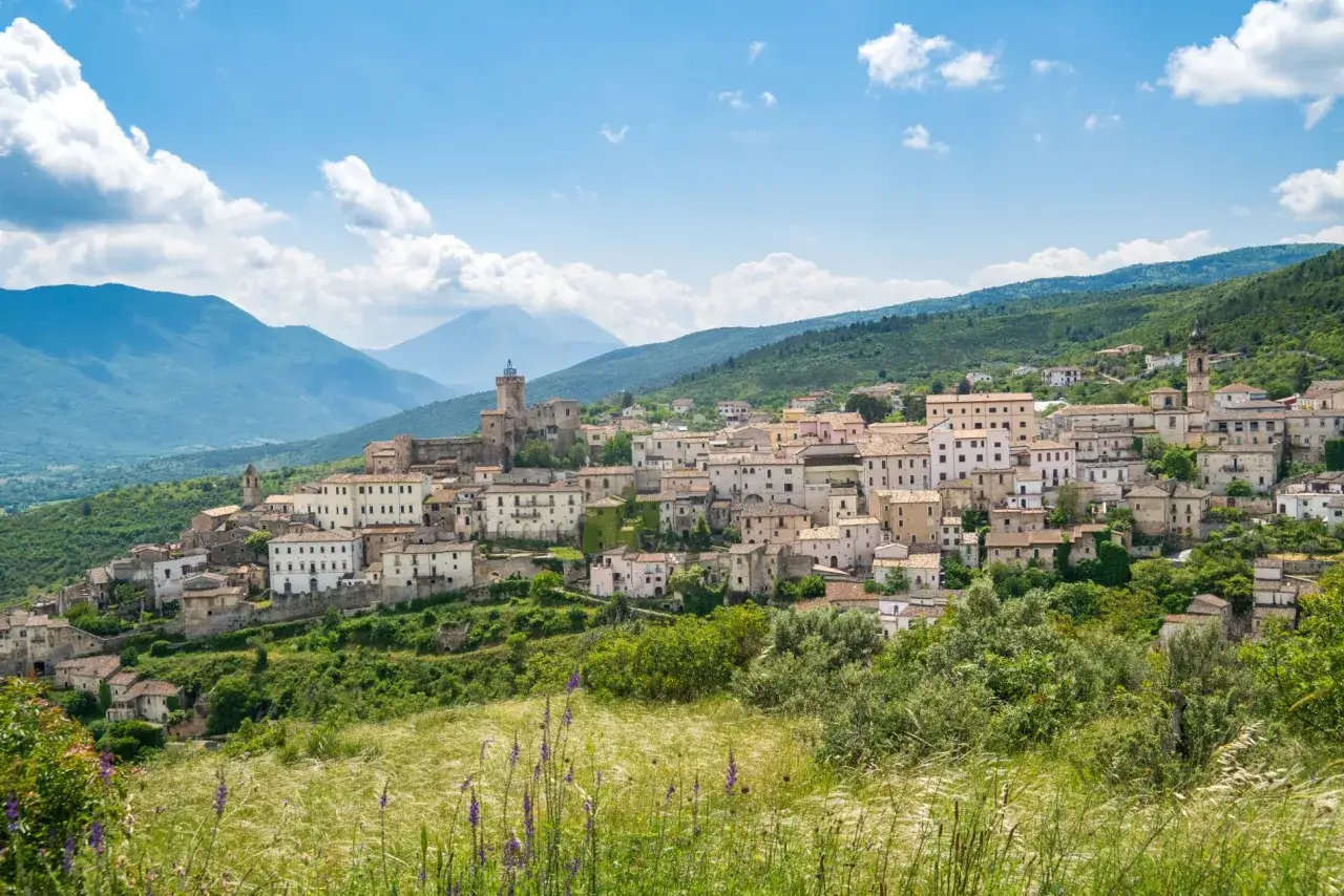 Panoramica di Capestrano, borgo medievale con castello e case in pietra, incastonato tra verdi colline e montagne. Cosa vedere in questo incantevole paesaggio abruzzese.