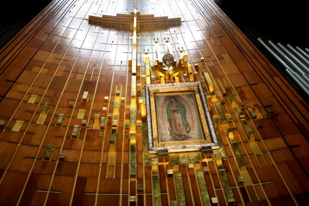Obraz Matki Bożej z Guadalupe w złotej ramie, umieszczony na drewnianej ścianie z metalowymi elementami. To miejsce pielgrzymek, gdzie wierni składają modlitwę do Matki Bożej z Guadalupe.
