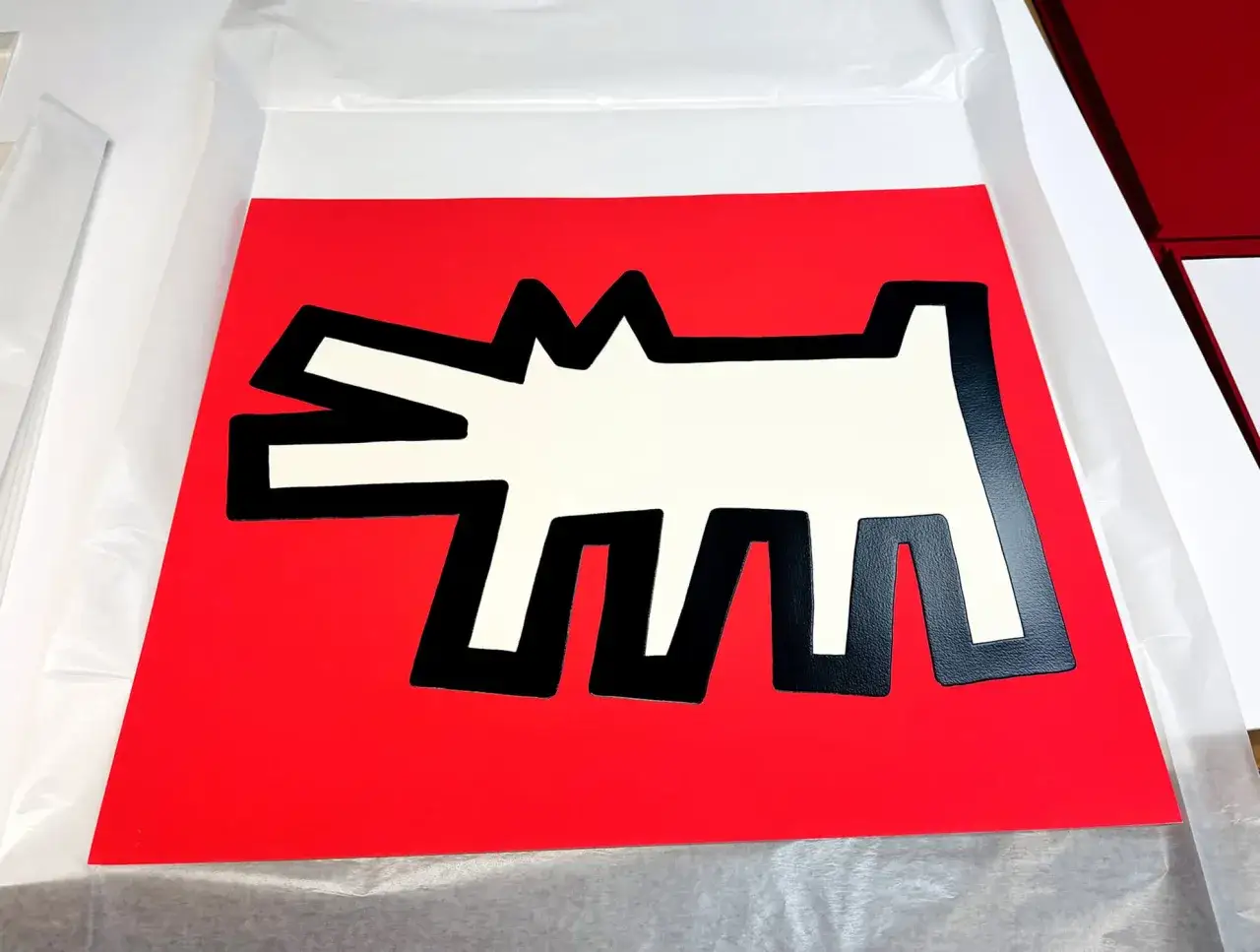 A bold Keith Haring barking dog artwork on a vibrant red background, outlined in black.
