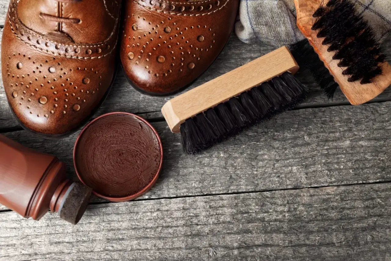 Bottes en cuir marron, cirage, applicateur et brosses pour un entretien parfait.