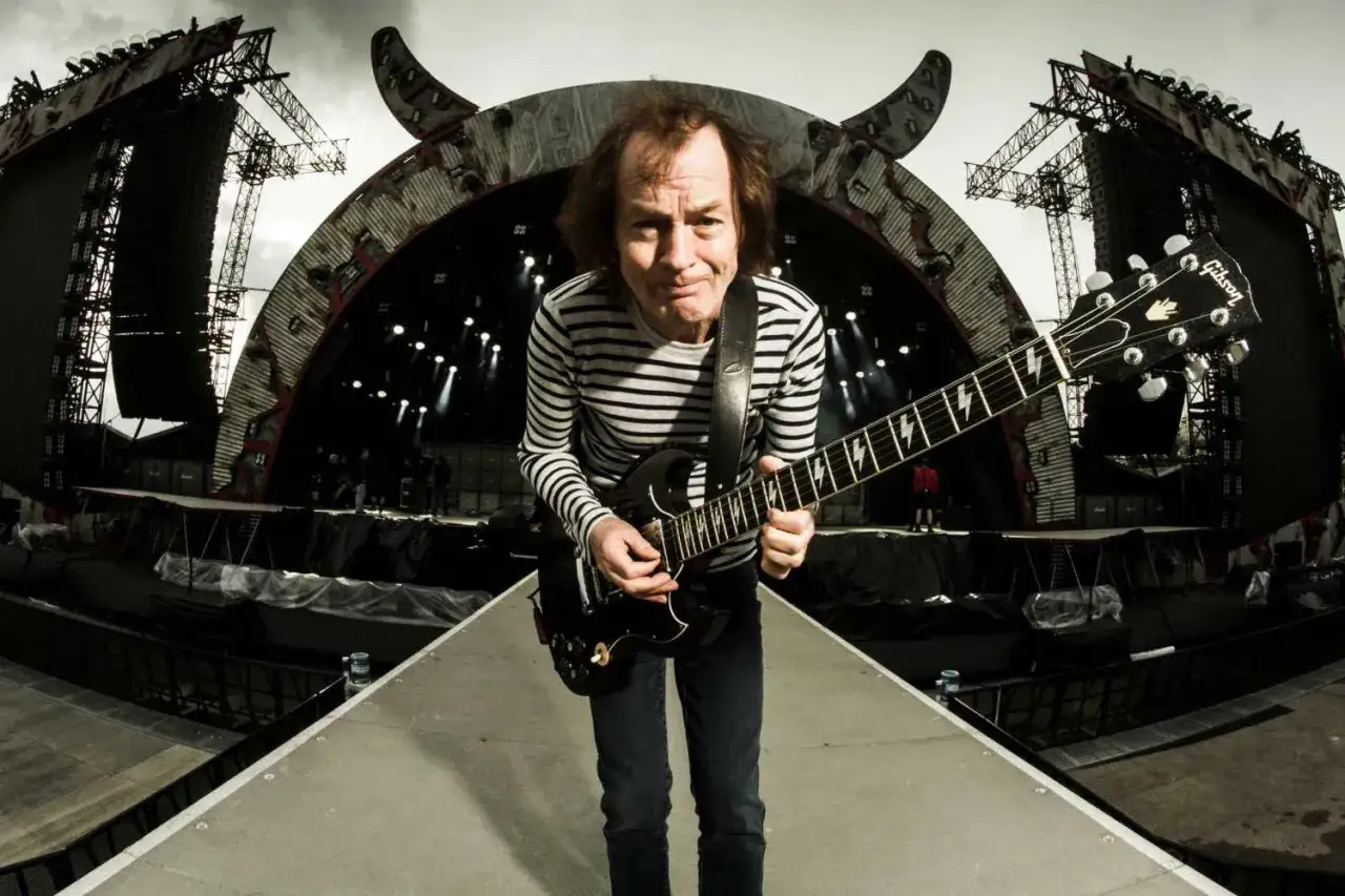 Angus Young von AC/DC spielt seine legend&auml;re ACDC Gitarre auf einer riesigen B&uuml;hne mit Teufelsh&ouml;rnern.