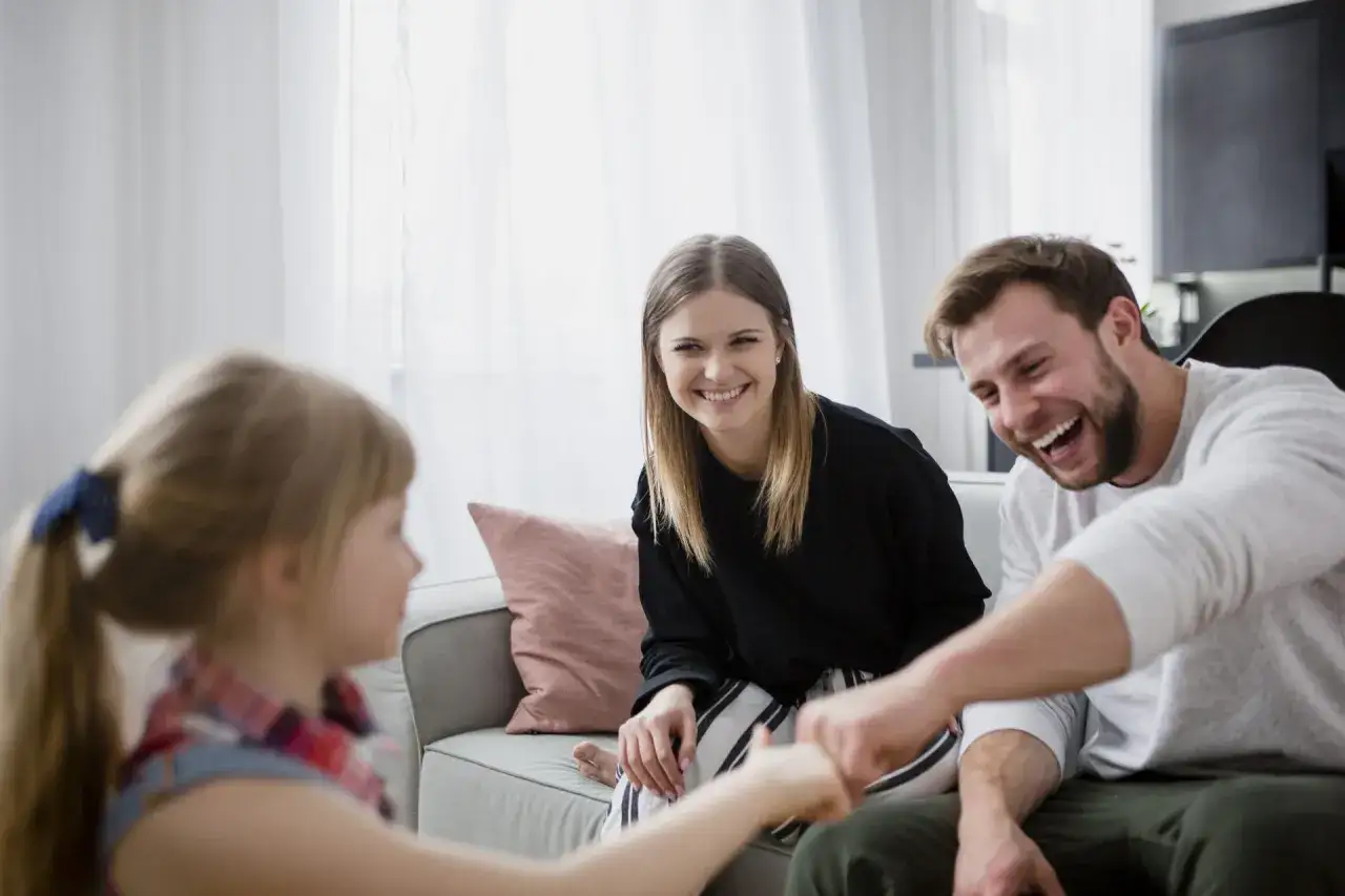 Rodzina śmieje się razem, pokonując lęk przed odrzuceniem. Dziecko gra z rodzicami.