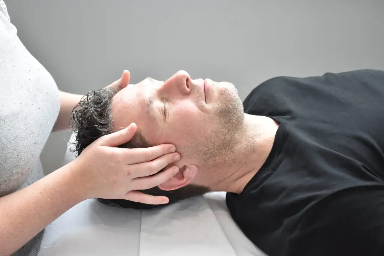 Mani che accarezzano la testa di un uomo, in una sessione di terapia cranio sacrale. Non sono noti effetti collaterali.