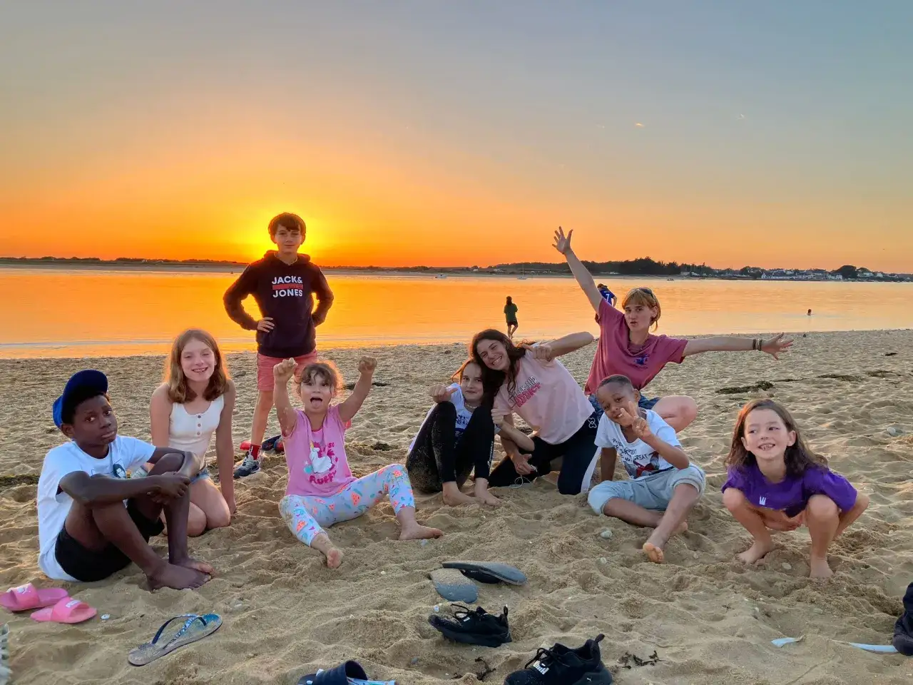 Des enfants joyeux profitent d'un coucher de soleil sur la plage, une belle colonie à la mer.