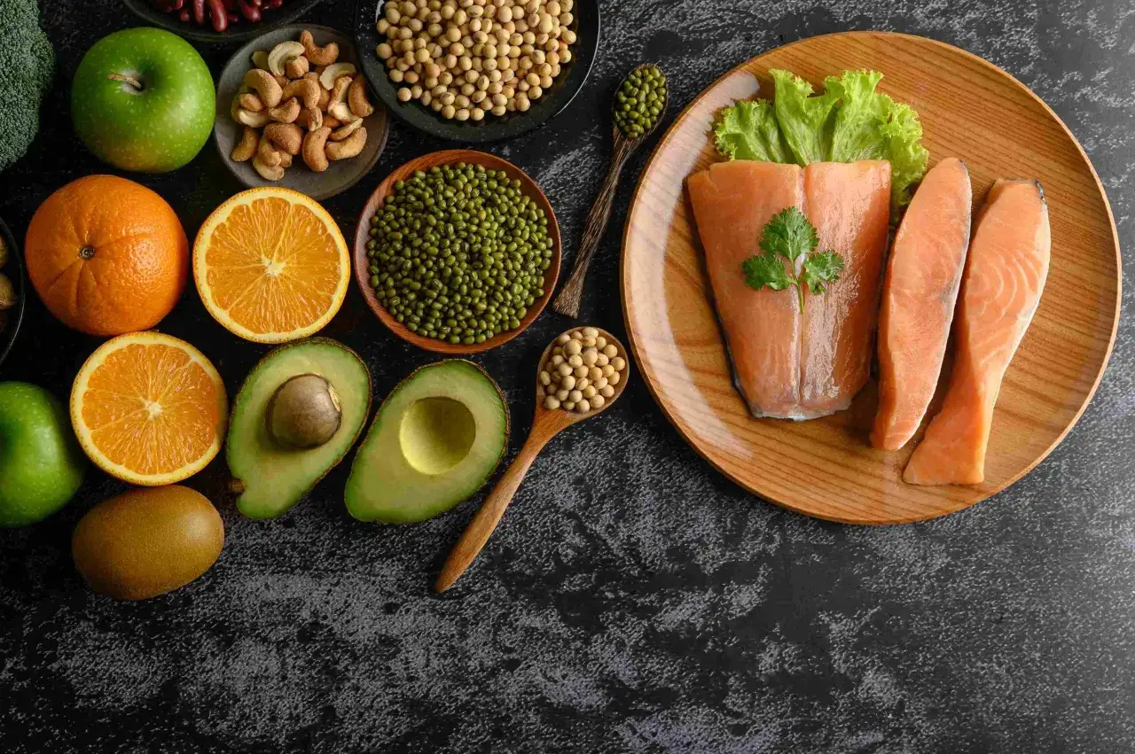 Assiette de saumon, avocats, oranges, pommes, kiwis, noix, haricots mungo et soja. Ces aliments sont riches en nutriments, dont la vitamine K2, aux multiples bienfaits pour la sant&eacute;.