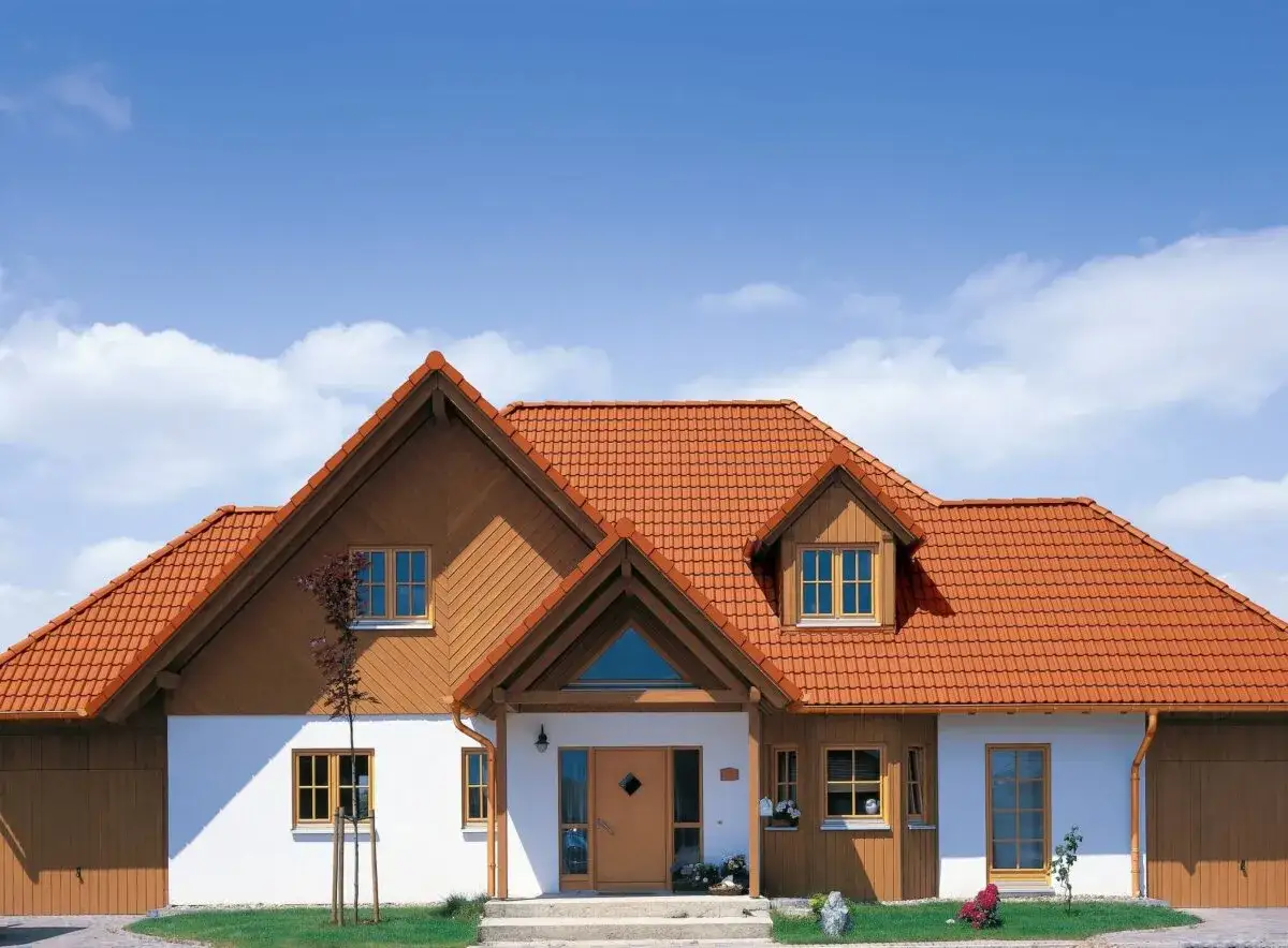Dom z pomarańczowym dachem, kt&oacute;ry może być wykonany z dach&oacute;wki betonowej lub ceramicznej.