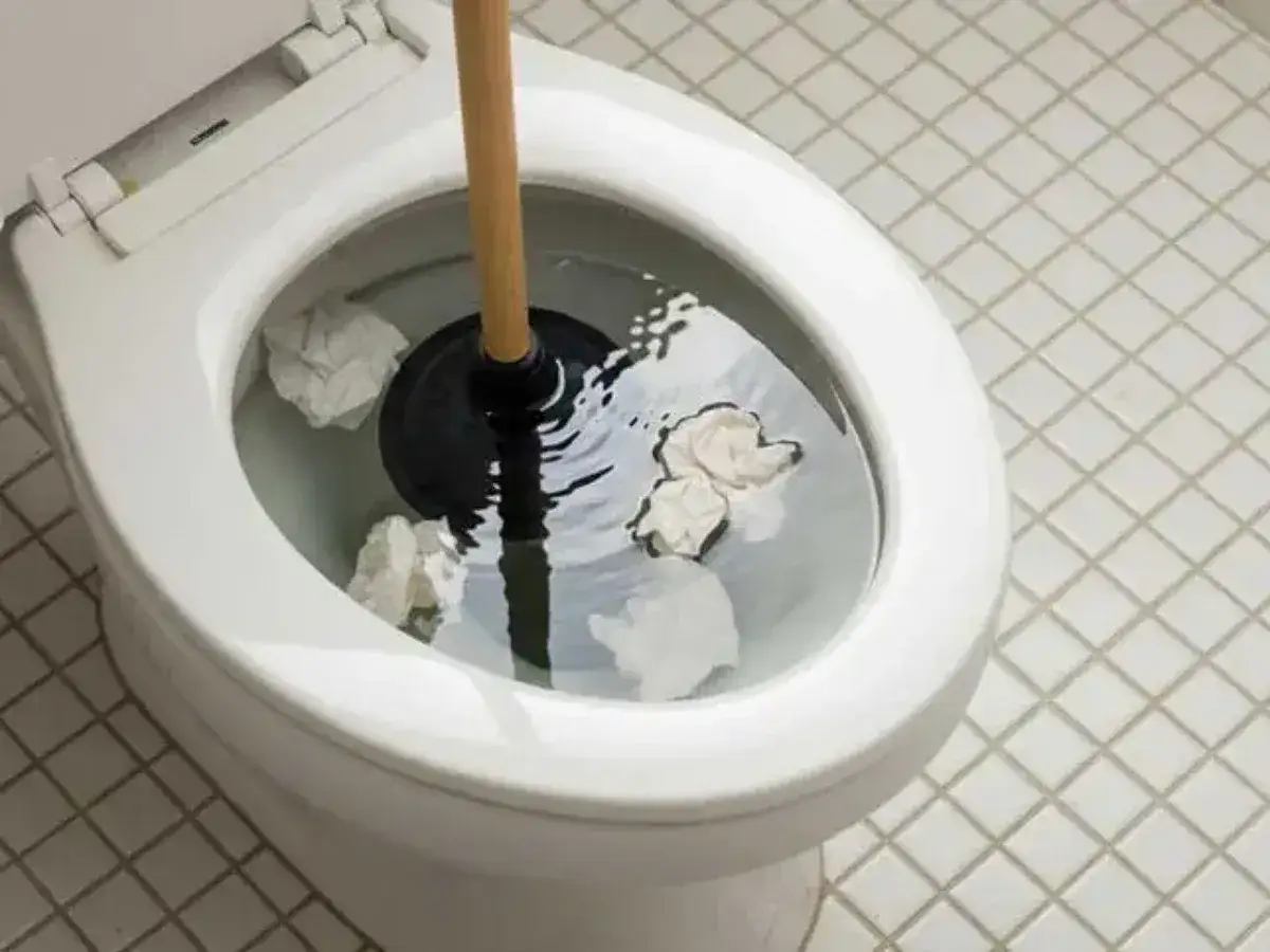 Strofinaccio e stantuffo in un water otturato. Tentativo di smontare wc otturato con carta igienica.