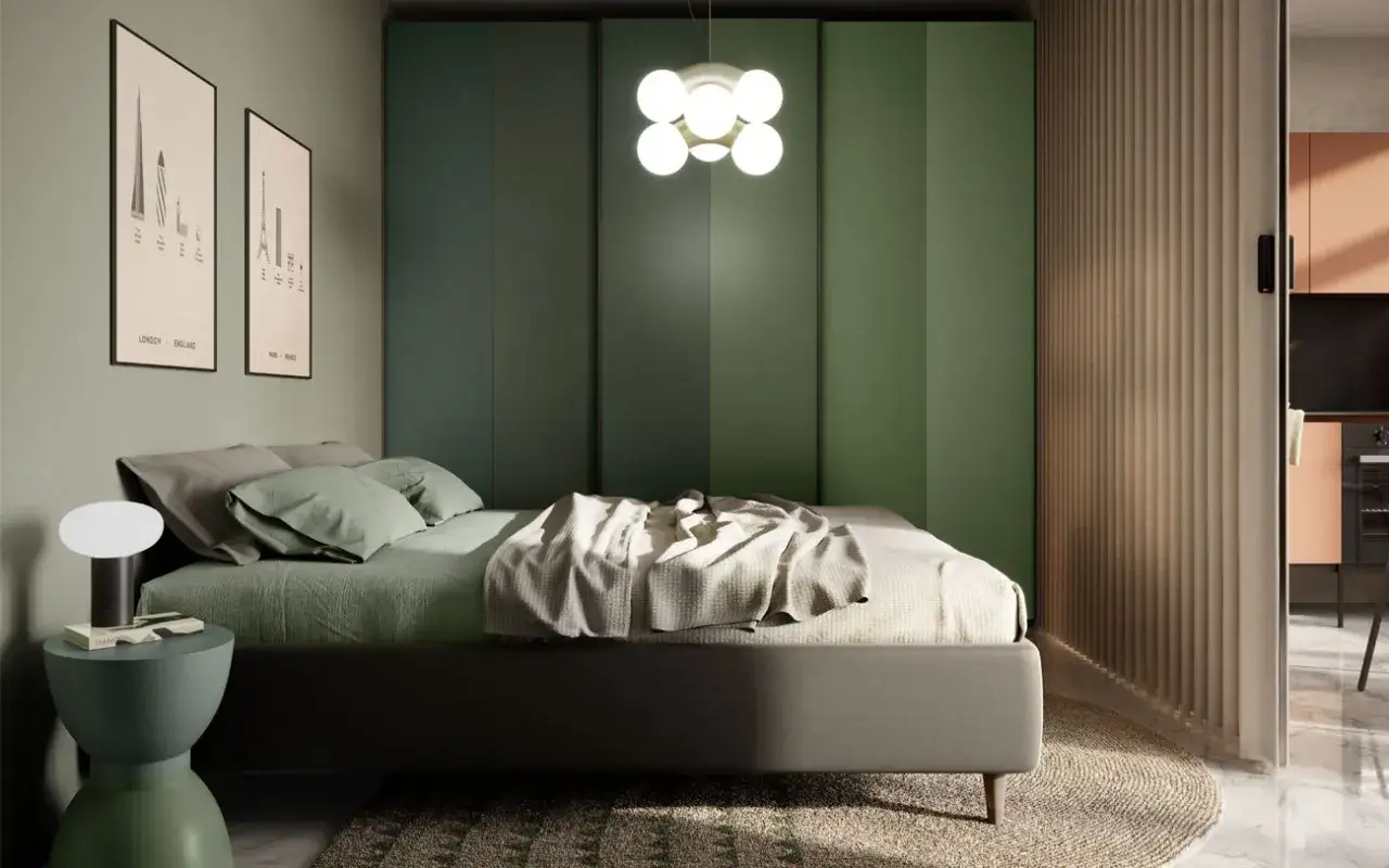 Camera da letto moderna con pareti verde scuro, letto con lenzuola verdi e coperta chiara, lampada da comodino e quadri con skyline.
