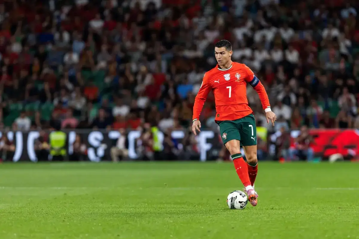 Cristiano Ronaldo w czerwonej koszulce z numerem 7, prowadzi piłkę na boisku. Jego gra wpływa na rankingi reprezentacji Portugalii w piłce nożnej mężczyzn.