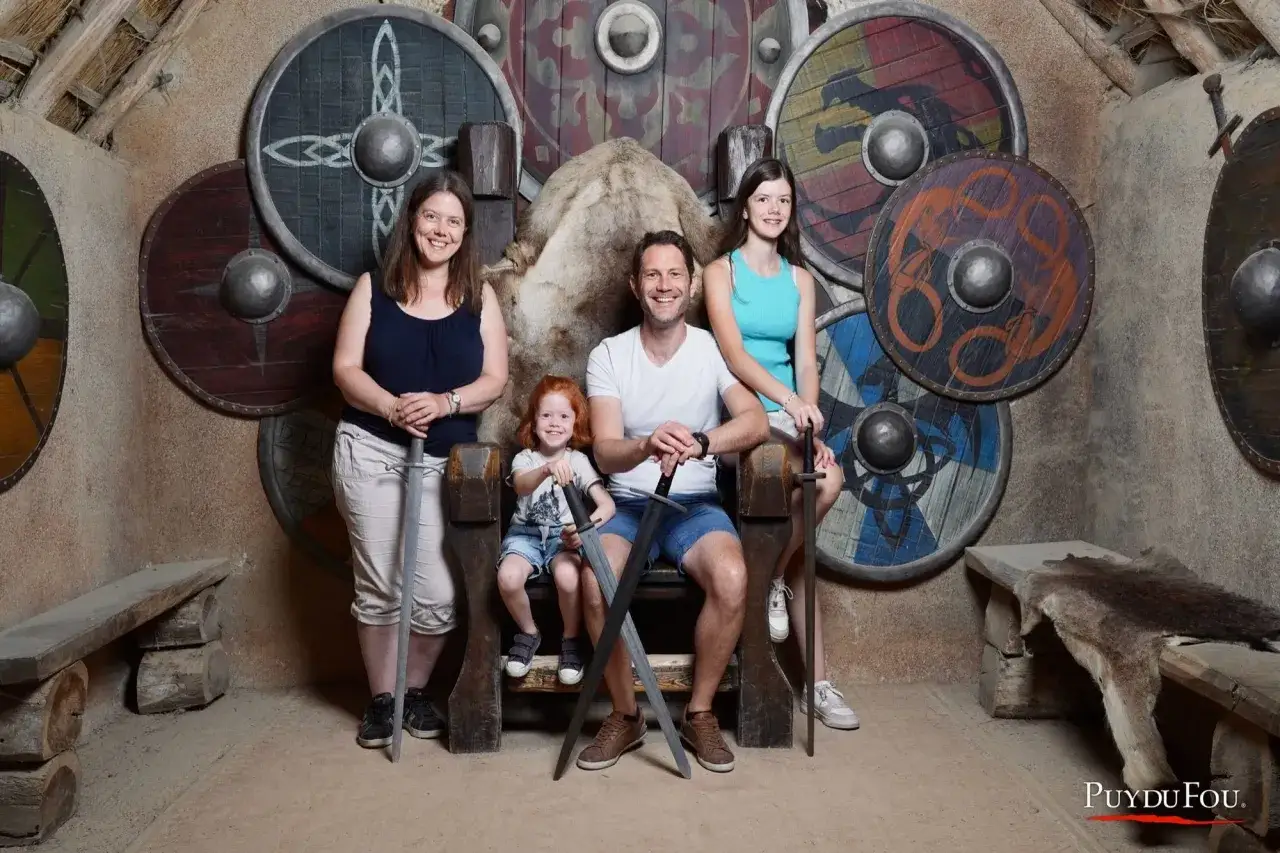 Une famille pose devant des boucliers vikings au Puy du Fou, un souvenir mémorable pour tous les âges.