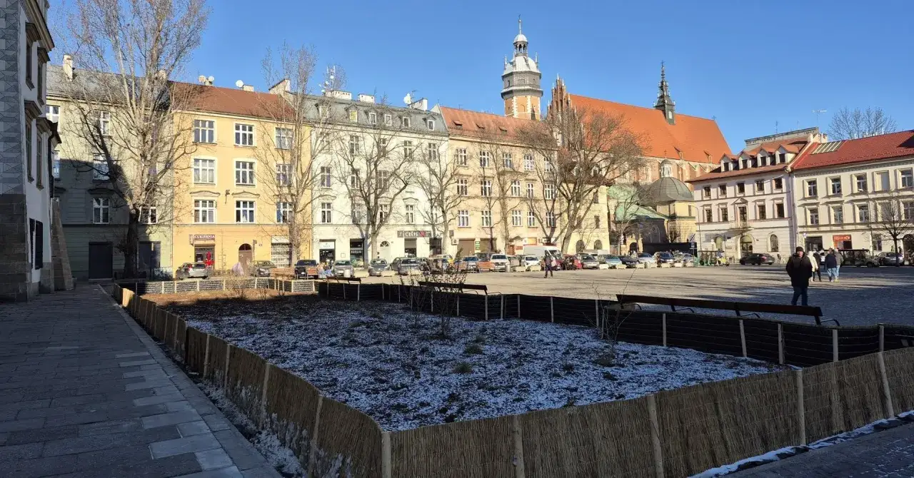 Zimowy rynek na Kazimierzu w Krakowie, z placem w trakcie przygotowań do wiosny. W tle kamienice i kości&oacute;ł.