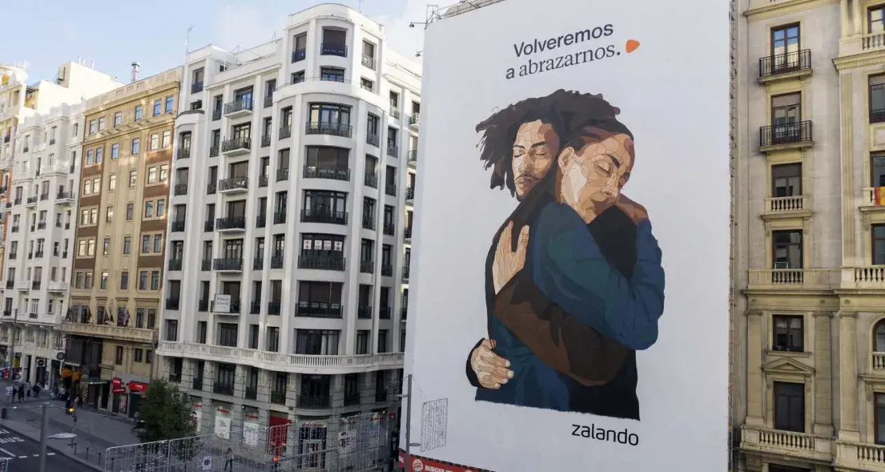 Un abrazo reconfortante en un anuncio de Zalando, un ejemplo de street marketing que evoca cercan&iacute;a y esperanza.