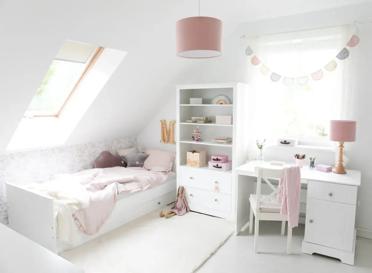 Pokój dziecięcy z białym łóżkiem, regałem i biurkiem. Różowa lampa i girlanda tworzą przytulną atmosferę, sprzyjającą spokojny sen dziecka.