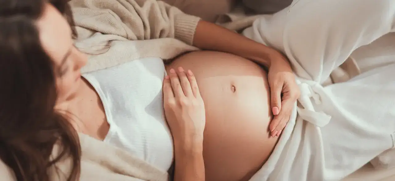 Kobieta w ciąży z dodatnim wynikiem GBS, czule dotyka brzucha. Współżycie w ciąży jest bezpieczne, gdy przestrzega się zaleceń lekarza.
