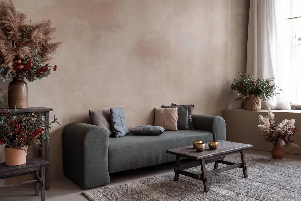 Gem&uuml;tliches Wohnzimmer mit Sofa, Holztisch und rustikalen Dekorationen. Die Wand ist mit einer nat&uuml;rlichen lime wash Technik gestaltet.
