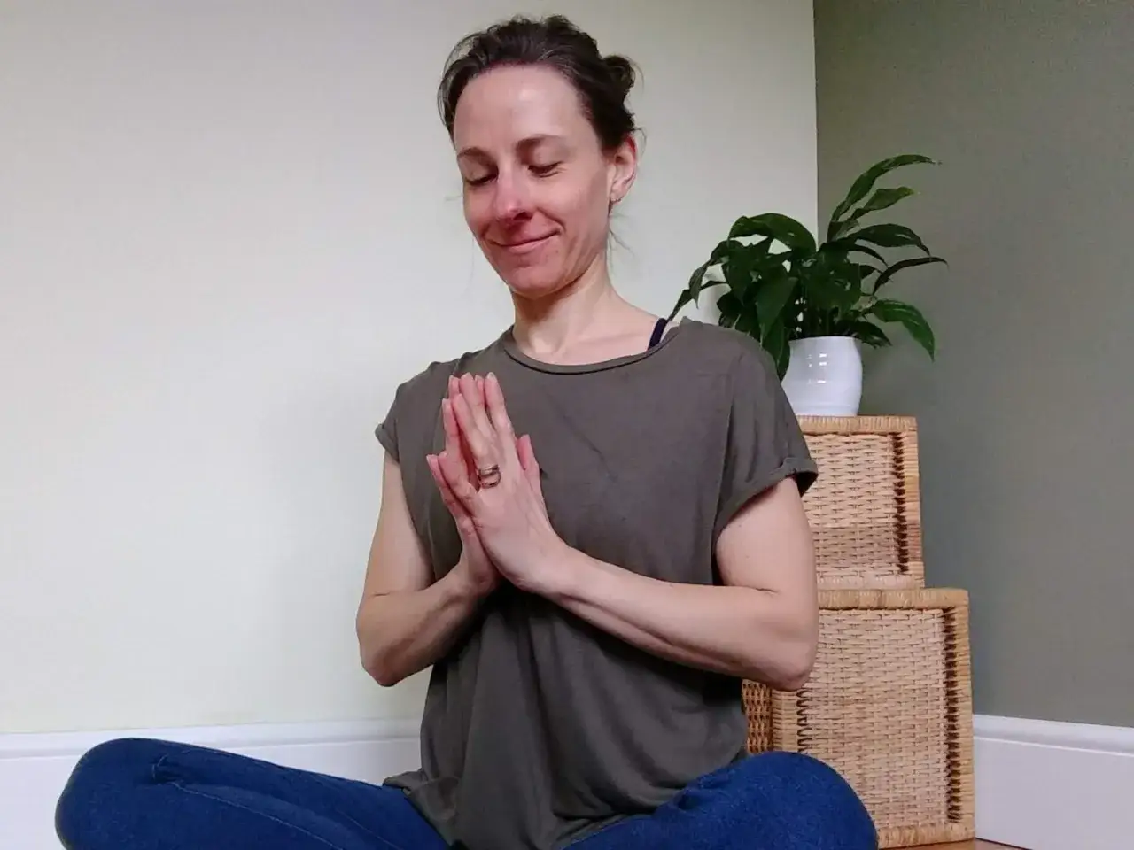 Kvinna i meditationsställning med slutna ögon och händerna i namaste. Hon utstrålar lugn och frid, ett sant namaste språk.