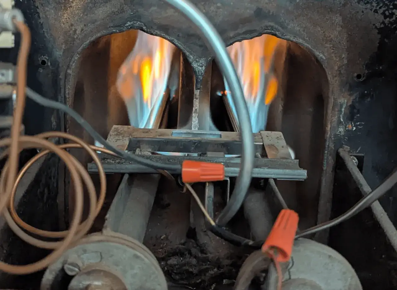 Fiamme blu e gialle danzano nel bruciatore della caldaia, segno di un funzionamento efficiente dopo la pulizia.