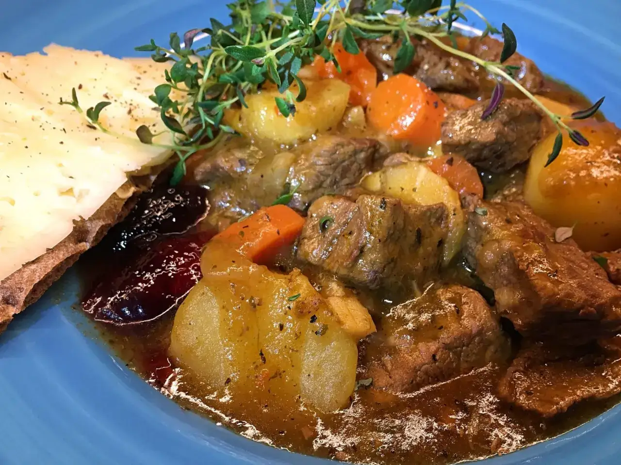 En mustig gryta med mört kött, potatis och morötter, perfekt för ett slow cooker recept. Serveras med lingon och en bit bröd.