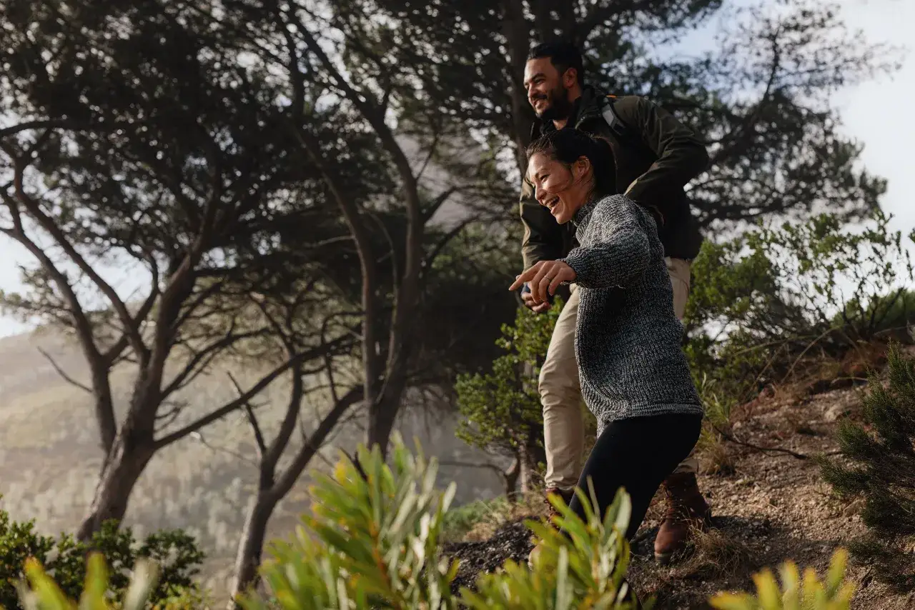 Coppia felice fa trekking, un uomo e una donna ridono mentre esplorano la natura. Forse questo &egrave; il segreto per sapere come avere una fidanzata: condividere avventure!