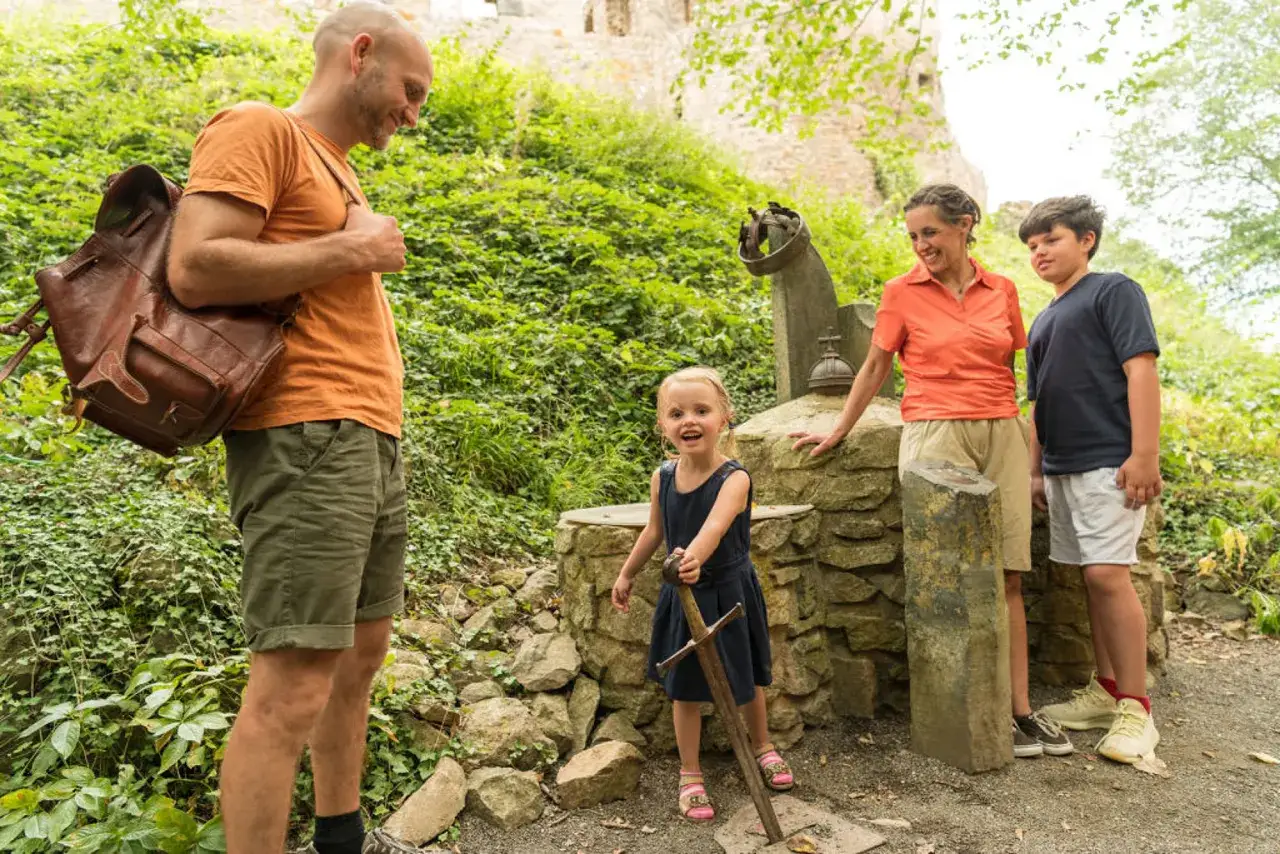 Familie erkundet die Eifel mit Kindern. Ein kleines M&auml;dchen zieht stolz ein Schwert aus einem Stein.