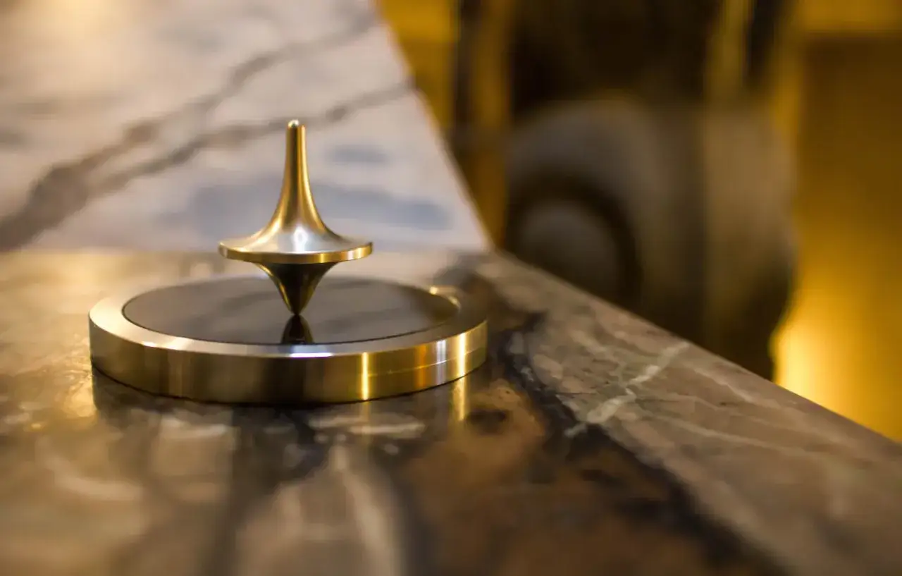 Toupie dorée en équilibre sur un socle, un exemple de force centrifuge en action.