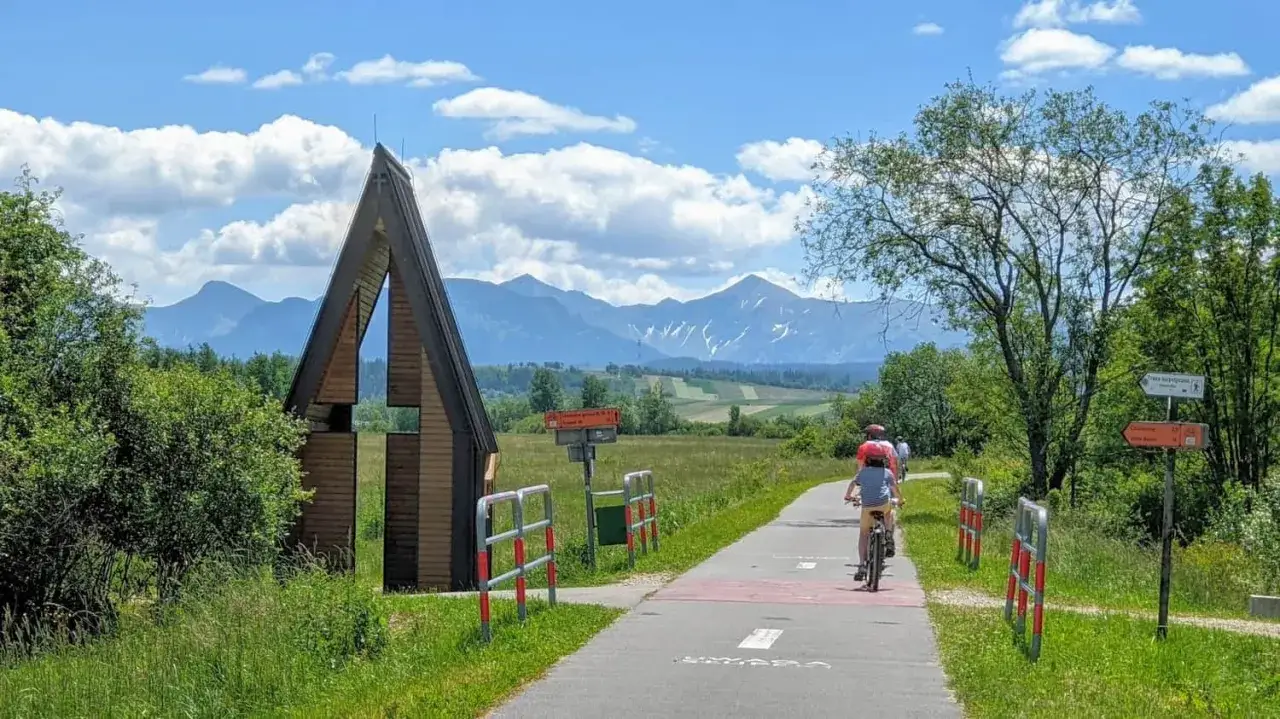 Rodzina na rowerach podziwia Tatry. Marzenie o rowerem dookoła Tatr w jeden dzień staje się rzeczywistością na malowniczej ścieżce.