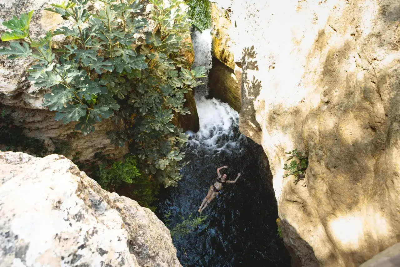 Una mujer nada en las aguas oscuras bajo una cascada. Estas son fotos del Salto del Usero, un lugar idílico.